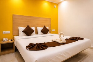 Une chambre d’hôtel avec un lit, une table de chevet, un téléphone et une serviette en forme de cygne.