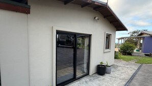 Ein modernes Gebäude mit einer großen Schiebeglastür, einem kleinen Fenster und einem Betonweg.