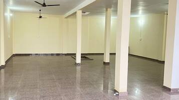 A spacious room with a polished floor, ceiling fans, and columns.