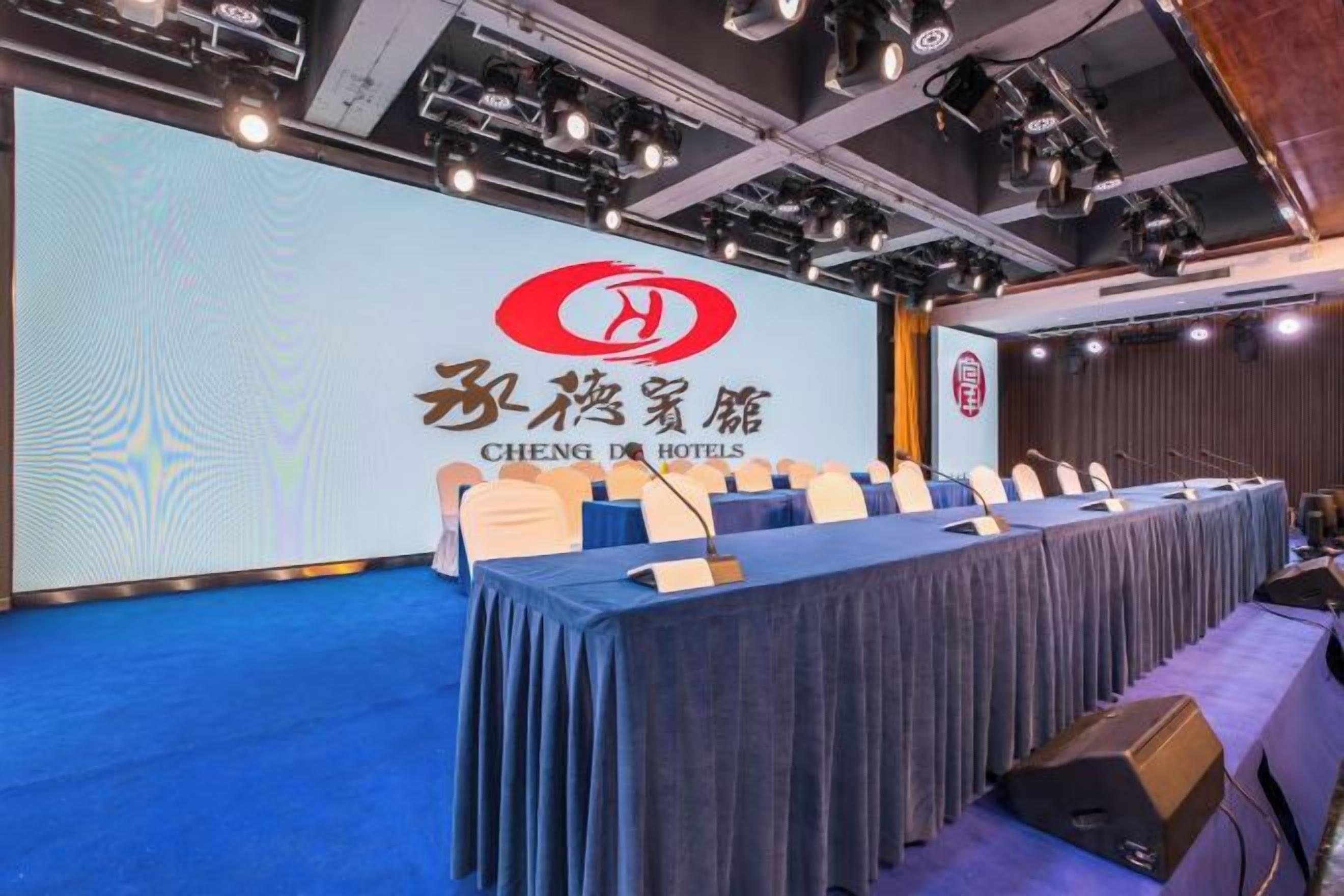 A conference room with a long table, chairs, and a presentation screen with hotel branding.