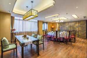 A dining area with a table set for four, surrounded by chairs, and a chandelier above. - Chengde Hotel (Mountain Resort) (Chengde)