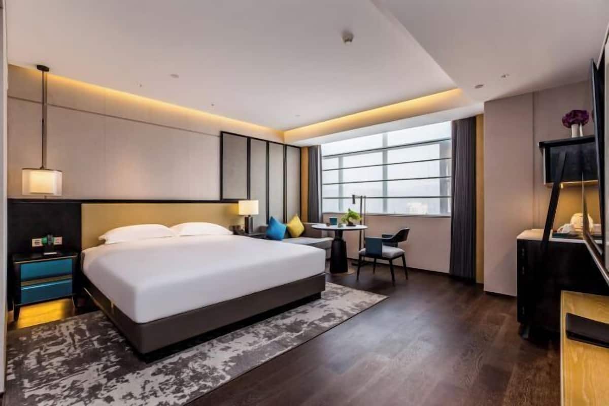 A modern hotel room with a large bed, bedside tables, a desk, and a chair.