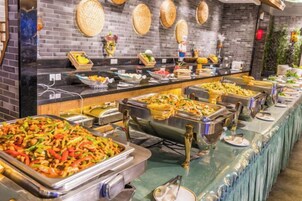 A buffet with various food items and a brick wall with circular decorations.