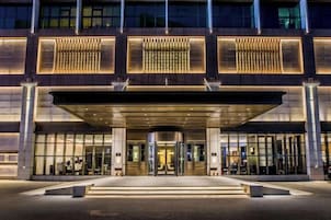 A modern hotel entrance with a covered entrance, glass doors, and a well-lit facade.