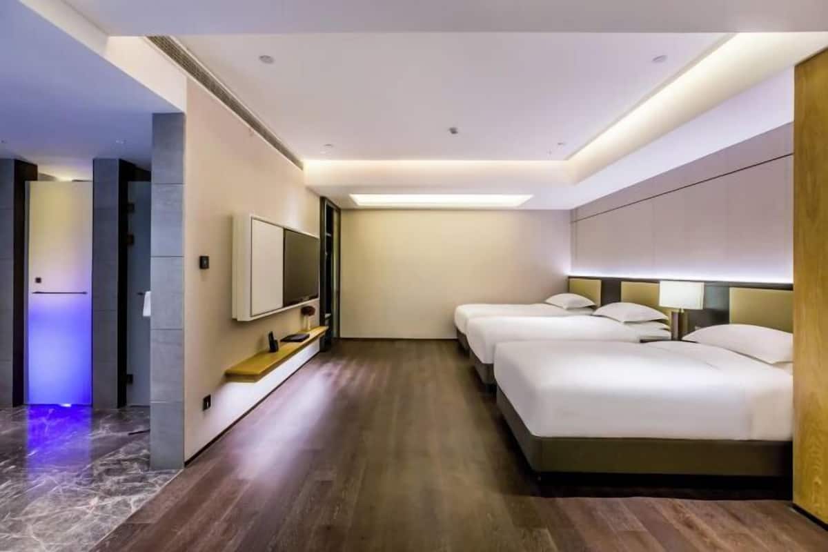 A modern hotel room with a large bed, a TV, and a wooden headboard.