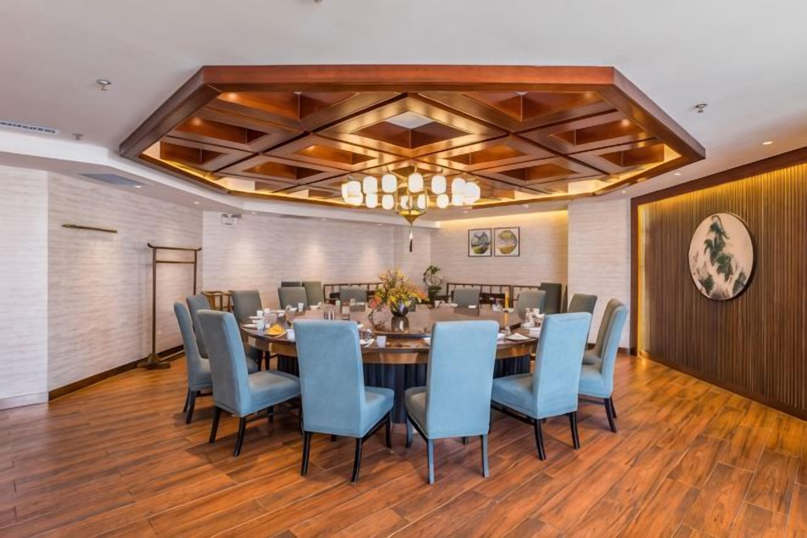 A dining area with a round table, six chairs, and a chandelier.