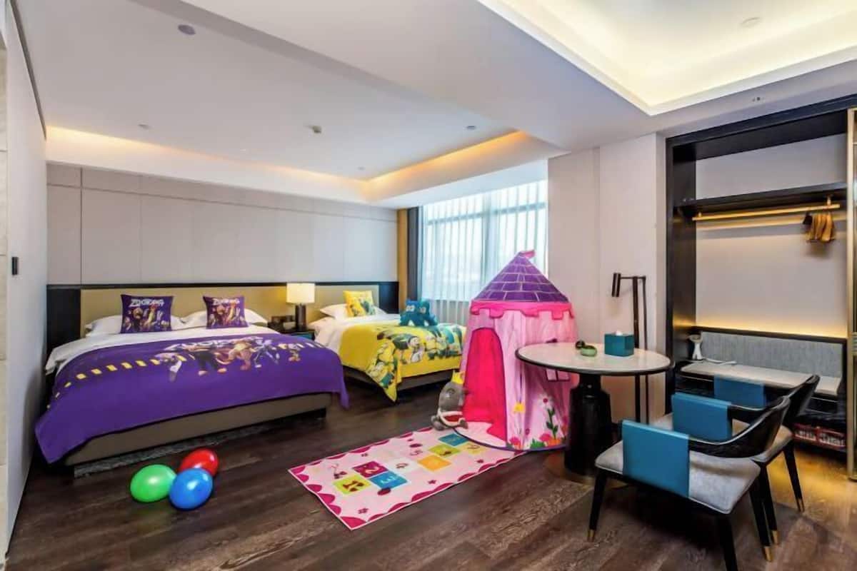 A hotel room with a bed, a small play tent, a round table, and a seating area.