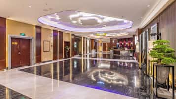 A hotel lobby with a polished floor, a reception desk, and a bar area.