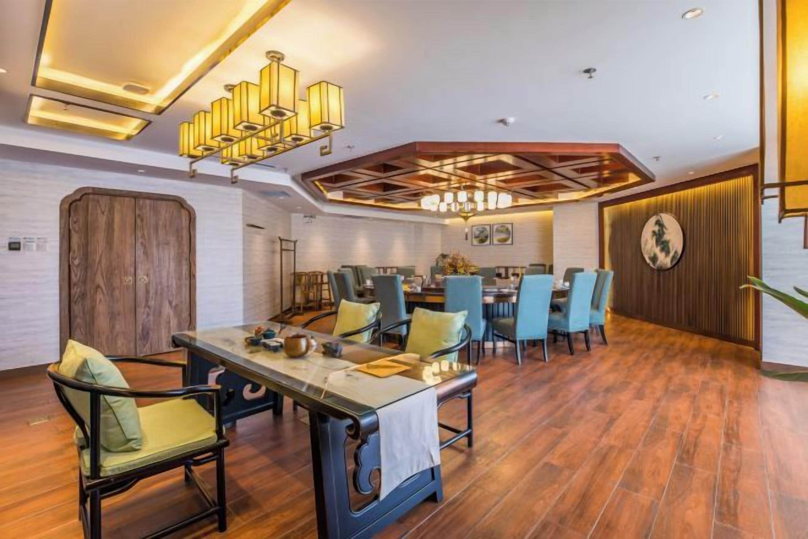 Un espace repas avec une table et des chaises en bois, un lustre et un design moderne au plafond.