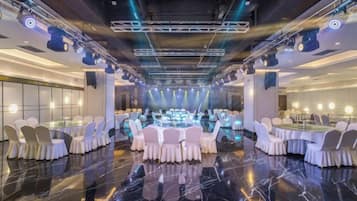Une salle de banquet avec des tables rondes et des chaises, un sol en marbre poli et un design de plafond moderne.