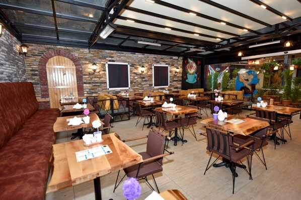 A restaurant with wooden tables and chairs, stone walls, and a mural. - Royal Garden Suite Hotel (Istanbul)