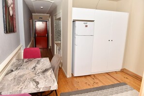 A compact kitchen with a refrigerator, a dining table, and a red chair. - Royal Garden Suite Hotel (Istanbul)
