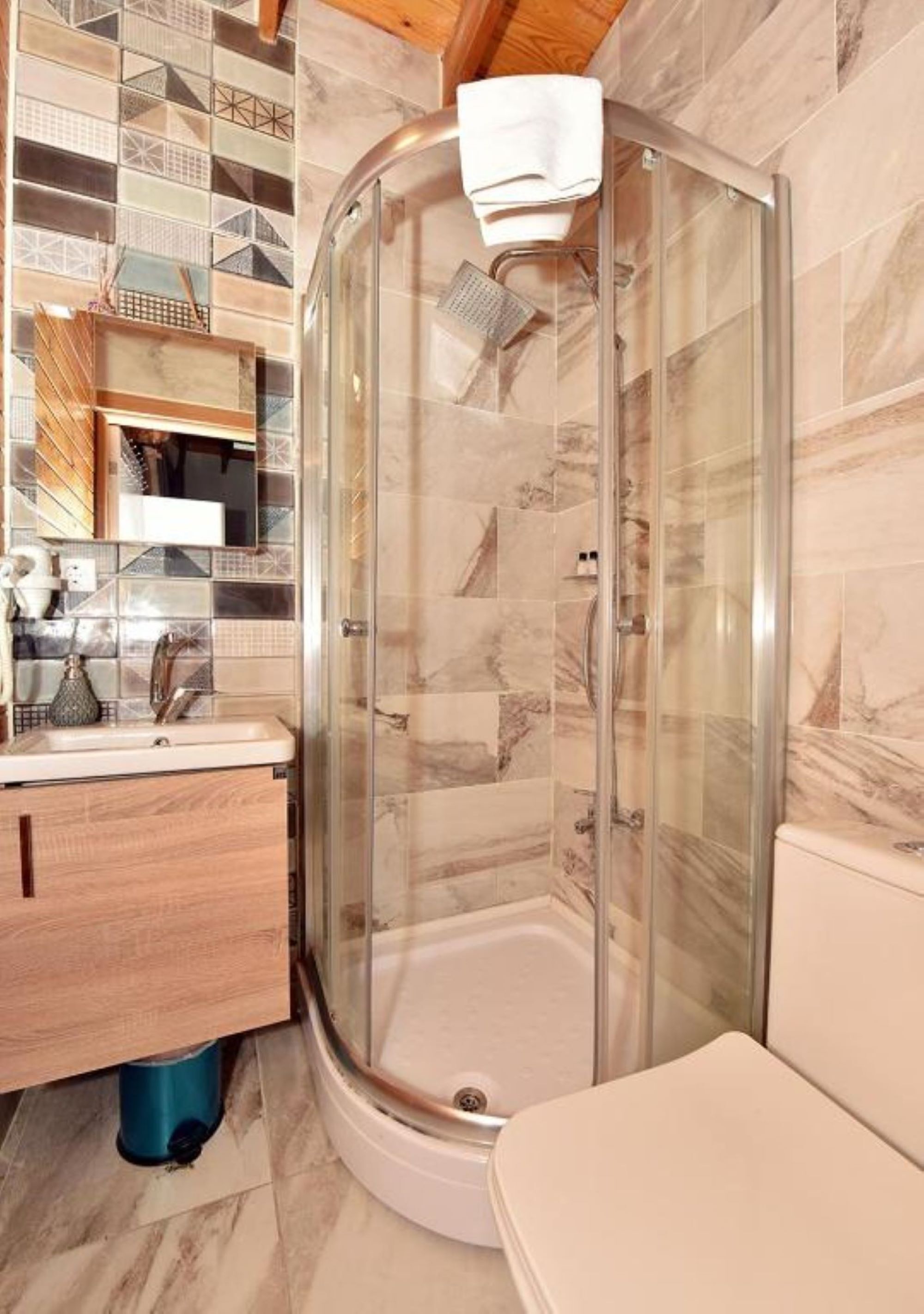 A bathroom with a glass-enclosed shower, a sink, and a toilet.