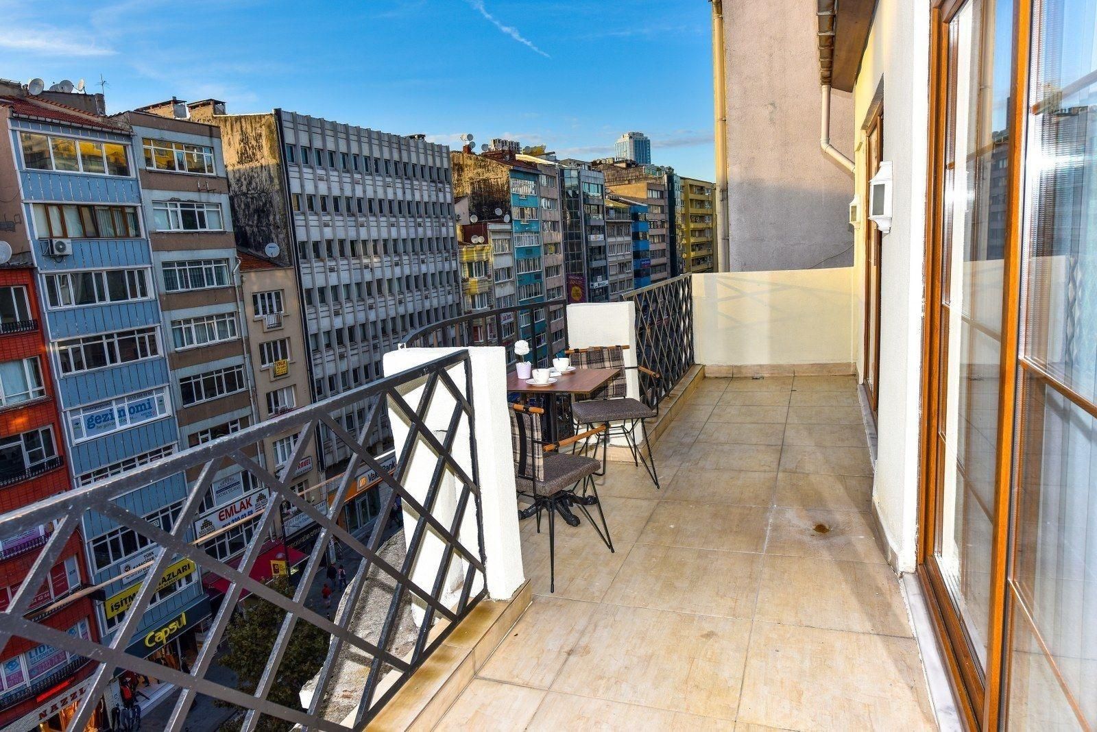 Un balcon avec une table et des chaises, donnant sur un paysage urbain composé de différents bâtiments.