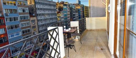 Un balcon avec une table et des chaises, donnant sur un paysage urbain composé de différents bâtiments.