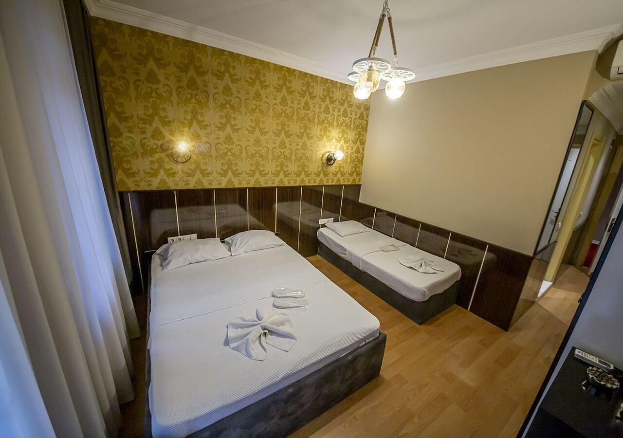 Ett hotellrum med en stor säng, en mindre säng, en kristallkrona och en spegel.