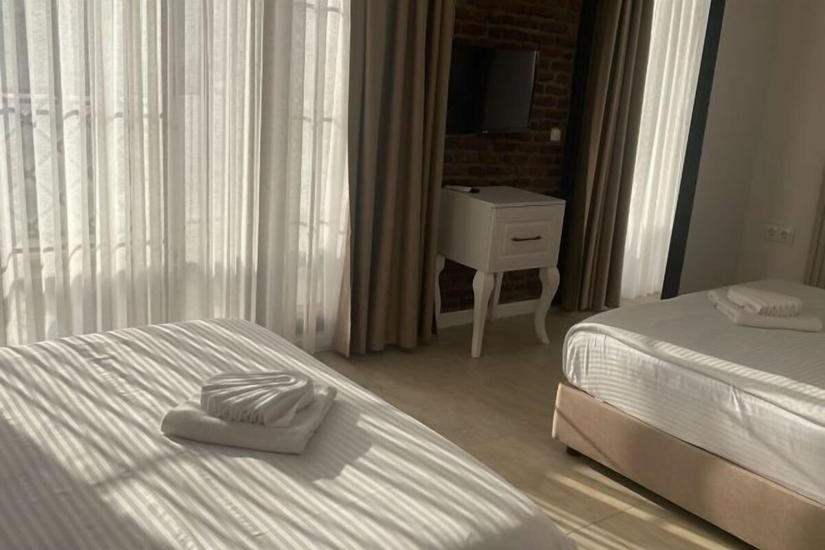 A hotel room with two beds, a desk, and a mirror.