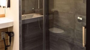 A modern bathroom with a glass-enclosed shower, a white sink, and a toilet. - Campanile Aubagne - Alta Rocca (Aubagne)
