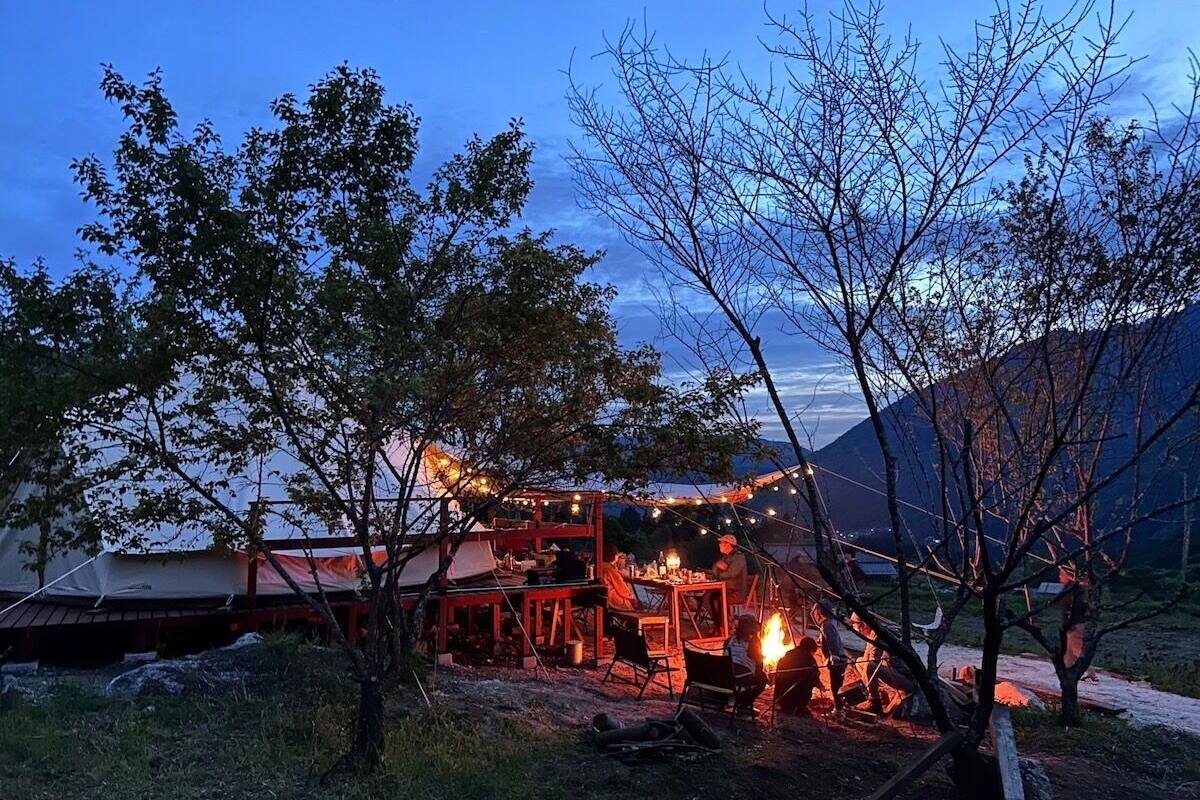 A campsite with tents and a dining area with string lights.