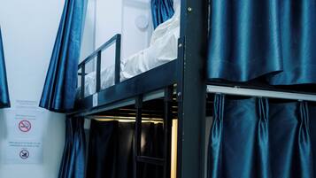 Habitación con literas, un armario azul y cortinas.