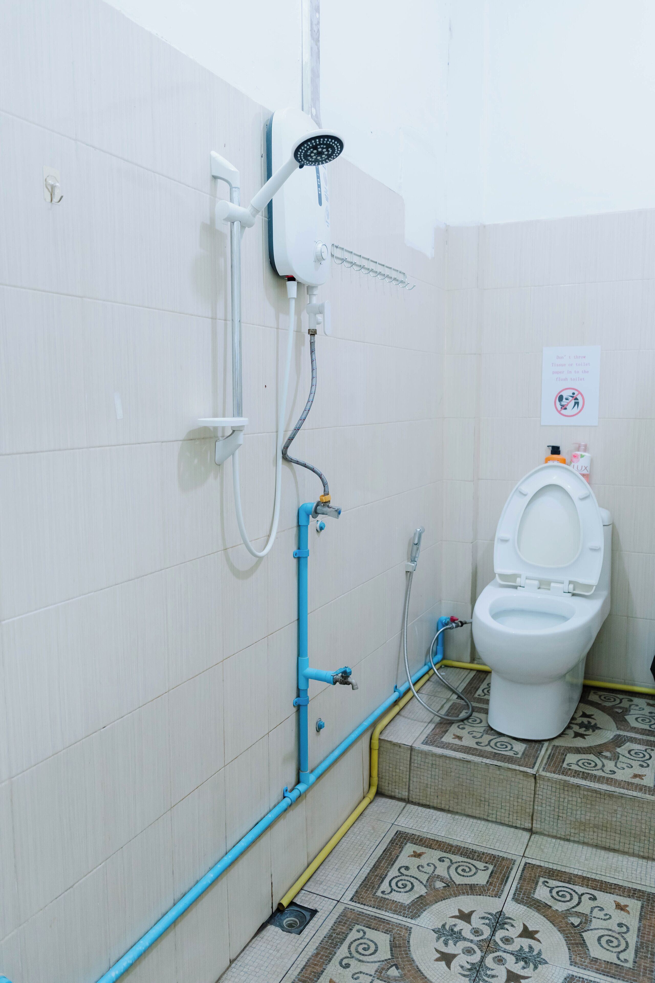 A bathroom with a shower, toilet, and tiled floor.