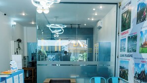 Un interior moderno con mostrador de recepción, zona de estar y separador de vidrio.