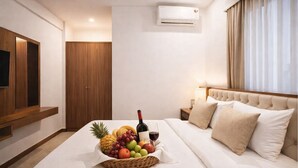 Hotellihuone, jossa on sänky, televisio, vaatekaappi ja seinälle asennettu ilmastointilaite.