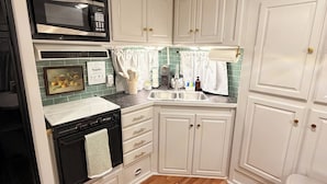 A compact kitchen with white cabinetry, a microwave, an oven, and a sink. - Sunset Hideaway (Springtown)