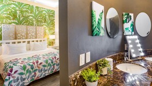 A hotel room with a bed, a bathroom with a vanity, and a wall with artwork. - Scala 306 1BD Condo for rent in Old Town, Puerto vallarta (Puerto Vallarta)