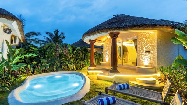 Un resort con piscina, sillas de descanso y una estructura de techo de paja.