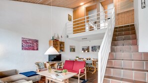 Un vaste espace de vie doté d’un haut plafond, d’un escalier et d’un coin repas.