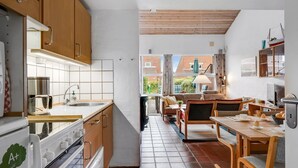 Une cuisine compacte avec des meubles en bois, un pare-feu en carrelage et un coin repas comprenant une table et des chaises en bois.