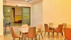 A dining area with a glass partition, cushioned chairs, and a table. - Bedone Hotel and Suites (Asaba)