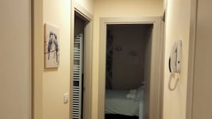 A narrow hallway with a tiled floor, a door leading to a bedroom, and a wall-mounted phone. - Appartamento in centro a Fermo, con tutti i comfort e parcheggio privato (Ascoli Piceno)