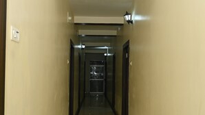 A corridor with a tiled floor, light fixtures, and doors leading to rooms. - Maurya Royal (Sasaram)