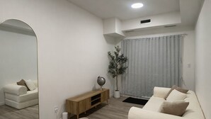 Ein modernes Wohnzimmer mit Esstisch, Sofa und einem großen Spiegel.