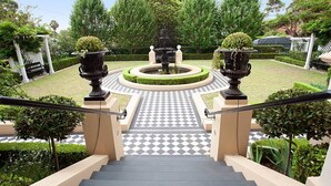 A staircase leading to a circular fountain surrounded by greenery and a checkered pathway. - Beautiful Studio in Heritage Building with Balcony (Lewisham)
