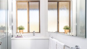 Ein modernes Badezimmer mit einem weißen Waschbecken, zwei Milchglasfenstern und einem Spiegel über dem Waschbecken.