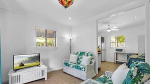 Ein Wohnzimmer mit Fernseher, Korbmöbeln und Deckenventilator.