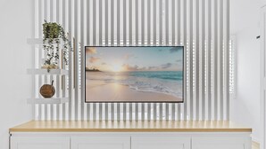 A wall-mounted flat-screen TV displaying a beach scene, a white shelf with decorative items, and a wooden counter below. - Studio4: Bondi Chic Interiors with Rooftop Pool (Bondi Junction)