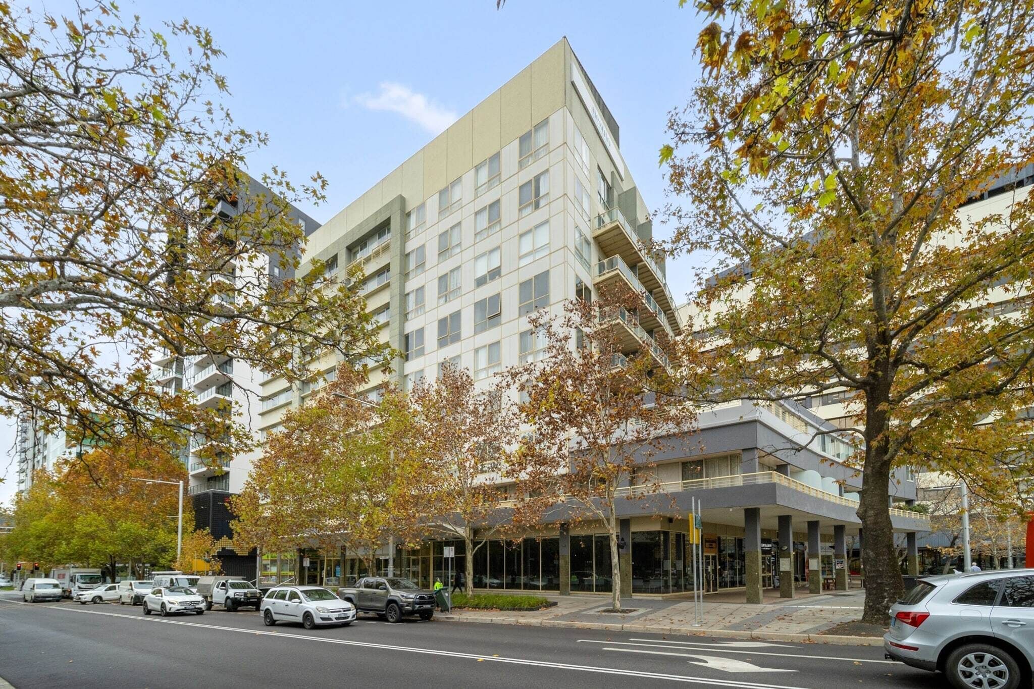 A modern building with a glass facade, multiple floors, and a covered entrance area.