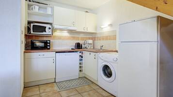 A compact kitchen with a microwave, coffee maker, dishwasher, and washing machine.