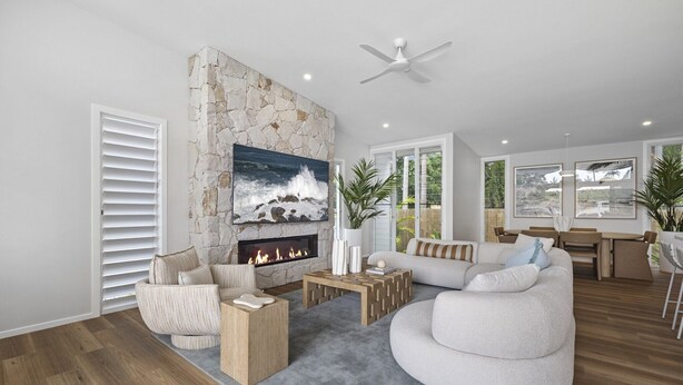 Een moderne woonkamer met een stenen openhaard, een groot schilderij en een eethoek met uitzicht op groen.