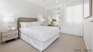 Een moderne hotelkamer met een groot bed, nachtkastjes met lampen, een plafondventilator en een groot raam met dunne gordijnen.
