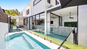 A modern house with a swimming pool, glass railings, and a covered patio area. - Spacious 3-Bedroom Retreat with BBQ and Pool (Coolum Beach)