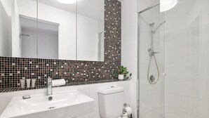 A bathroom with a white sink, toilet, and shower. - Luxury 2-Bed Apartment in Melbourne's Heart (Melbourne)