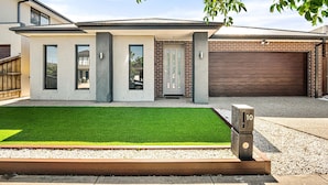 A modern two-story house with a garage, a well-maintained lawn, and a number 10 sign.