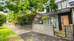 Ein modernes, zweistöckiges Haus mit Backsteinfassade, einer Holztür und der Hausnummer 158 an der Wand.