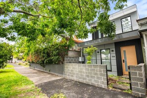 Ein modernes, zweistöckiges Haus mit Backsteinfassade, einer Holztür und der Hausnummer 158 an der Wand.