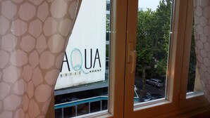 A window view of a hotel with a sign reading "AQUA HOTEL" and a reflection of trees and a street. - La Dolce Vita, a stone's throw from the beach. (rimini)